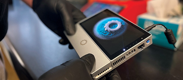 Photo of lab technician holding a MinION portable sequencer from Oxford Nanopore